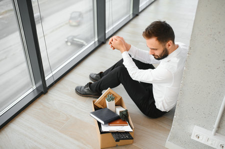 Sad fired businessman sitting outside meeting room after being dismissed.の写真素材