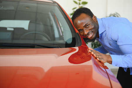 Handsome man is standing near his new car and smiling.の写真素材