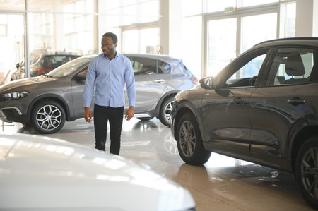 Handsome African man choosing a new car at the dealership.