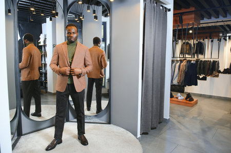 African Businessman in classic suit against row of suits in shop.