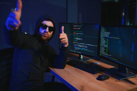 hacker sitting at desk in dark atmosphere. A computer programmer or hacker. Anonymous computer hacker. Hacker in dark roomの写真素材