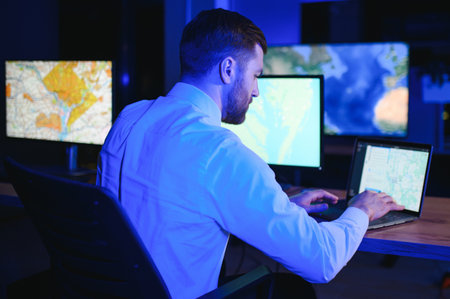 Male Data Scientist Works on Personal Computer Control and Monitoring Room. Map Surveillance of...
