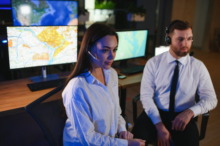Center of dispatching maintenance. Portrait of cheerful woman and man working via headset microphone while sitting on navigation controller board.の写真素材