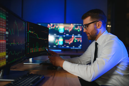 Side view of crypto broker sitting at office table, analyzing market, looking at screen.