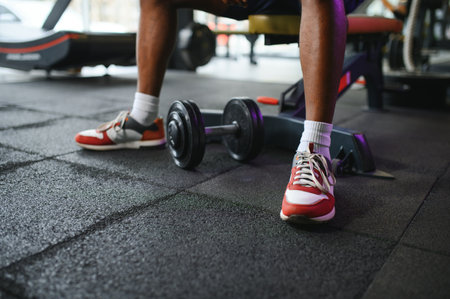 Young man strengthening biceps with dumbbell in gym.