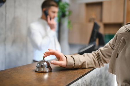 Hand of a woman using a hotel bell.