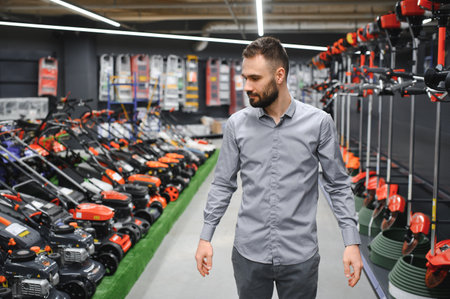 happy customer with electric lawn trimmer in hands at garden equipment store.