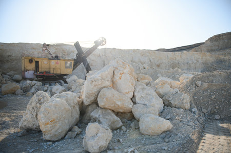 Hydraulic breaker hammer in a quarry for limestone mining with an excavator.
