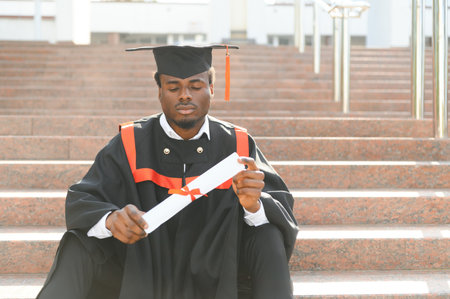 I have finally graduated. Happy young African man in graduation gowns holding diploma.