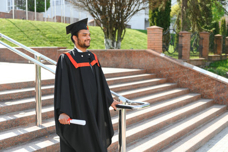 Handsome Indian graduate in graduation glow with diploma.