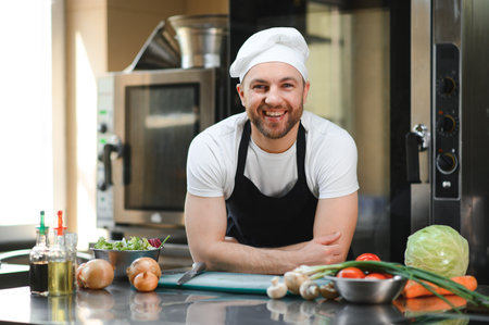 Portrait of a smiling male chef with cooked food standing in the kitchen.の写真素材