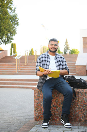 Handsome young Indian boy student with books and backpack. Education concept.