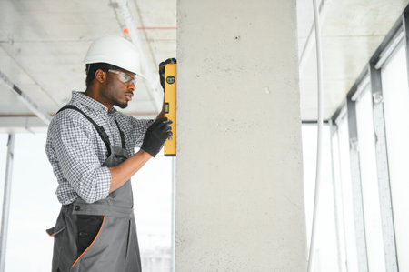 Construction worker observing and surveying wall alignment using water level.