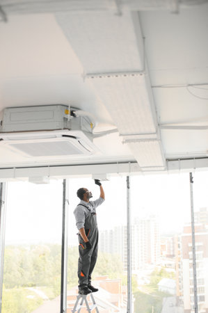 Industrial Theme. Warehouse Heating and Cooling System Installation by Professional Caucasian Technician. Commercial Building Ventilation Rectangle Channels. Air Distribution.の写真素材