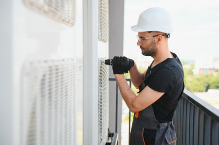 Young man repairman checking an outside air conditioner unit.