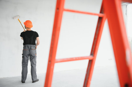 Building contractor painting gray wall with roller brush.の写真素材