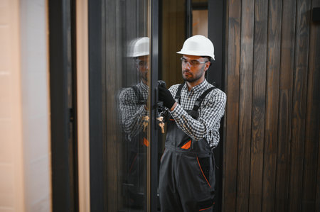 A worker or engineer in a uniform works on a construction site for the manufacture of wooden modular houses.の写真素材