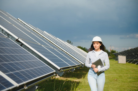 Portrait of beautiful female engineer technologist standing among solar panels.の写真素材