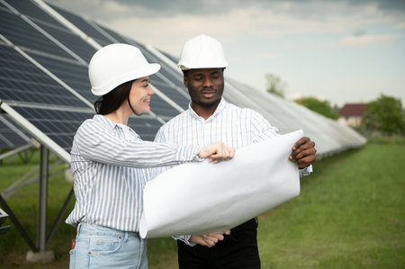 Male and female engineers worker working in solar panels power farm. technician working at solar...