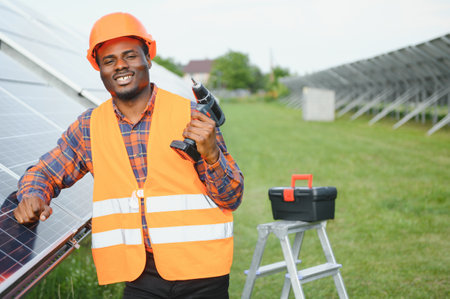 Portrait of African American electrician engineer in safety helmet and uniform installing solar...
