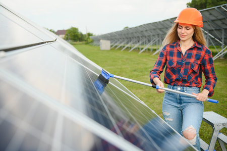 Woman worker washes solar panels. Green energy concept and solar panel care.