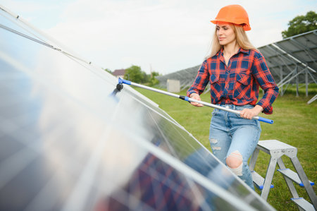 Woman worker washes solar panels. Green energy concept and solar panel care.の写真素材