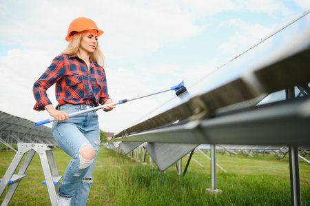 Woman Worker cleaning solar panels after installation outdoors.の写真素材
