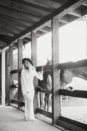 Beautiful model girl stands in a long dress with a horse.の写真素材