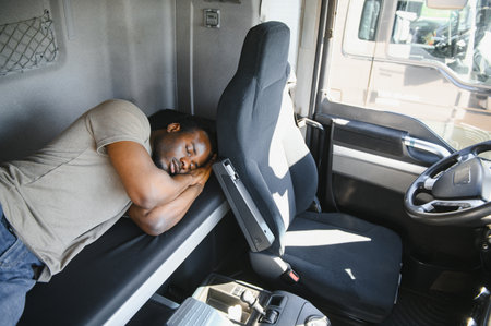 Truck driver sleeping in his cabin after working long routes overtime. Sleepy trucker taking a nap on a bed inside truck transporter. Lack of sleep.の写真素材