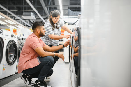 Young Multiethnic Couple Explores Home Electronics Store for Washing Machine Selection.の写真素材