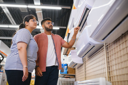 Young couple, satisfied customers choosing air conditioner in appliances store.の写真素材
