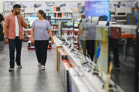 Beautiful couple buying consumer tech products in modern home appliances store. They are choosing home theater and TV devices.の写真素材