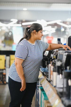 Smart modern female customer choosing coffee machine at electronics store.