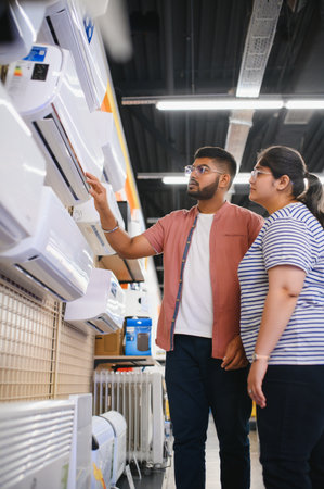 Young couple, satisfied customers choosing air conditioner in appliances store.の写真素材