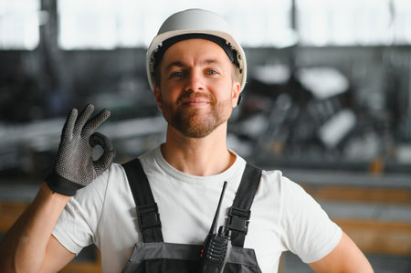 Men industrial engineer wearing a white helmet while standing in a heavy industrial factory behind. The Maintenance looking of working at industrial machinery and check security system in factory.の写真素材