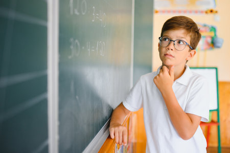 Funny schoolboy near the green school board in the classroom. Elementary school. Back to school.の写真素材