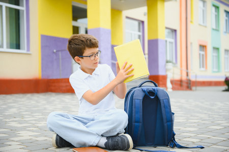 Portrait of a junior high school student sitting and reading a book near the school. Learning concept.の写真素材