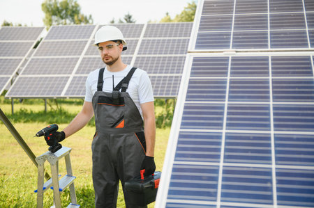 Portrait of a worker in uniform and white helmet working on solar panels.