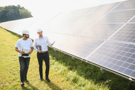Solar power plant with two engineers walking and examining photovoltaic panels. Concept of...