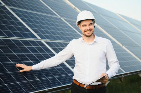 man in white shirt standing near photovoltaic panels on sunny day in countryside.の写真素材