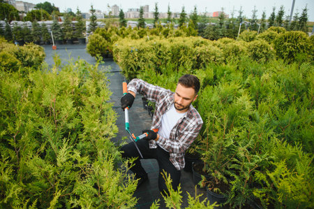 Portrait of a young handsome gardener. Shop of tree sprouts