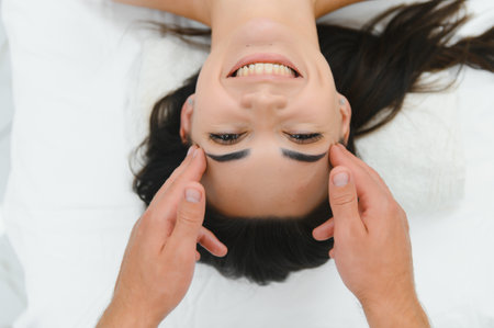 Beautiful young girl having face massage in spa salon.の写真素材