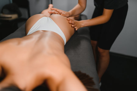 Beauty treatments for weight lost. Cropped shot of therapist or massager doing lymphatic drainage or anti cellulite massage on legs for woman client lying at spa center. Body care conceptの写真素材