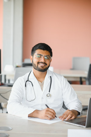 Portrait of happy friendly male Indian latin doctor medical worker wearing white coat with stethoscope. Medical healthcare concept.の写真素材
