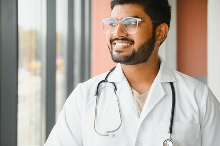 Portrait of happy friendly male Indian latin doctor medical worker wearing white coat with stethoscope. Medical healthcare concept.の写真素材