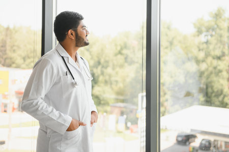 Portrait of happy friendly male Indian latin doctor medical worker wearing white coat with stethoscope. Medical healthcare concept.の写真素材