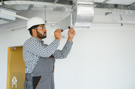 hvac indian worker install ducted pipe system for ventilation and air conditioning. copy space.の写真素材