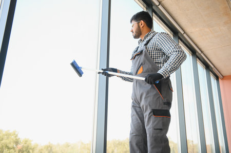 Cheerful male person cleaning window.
