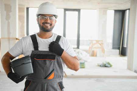 Portrait of young professional Indian worker in uniform and helmet. Construction and repair concept.