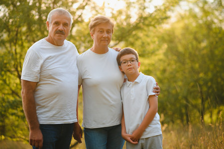 Grandparents walking with them grandson in summer sunset.